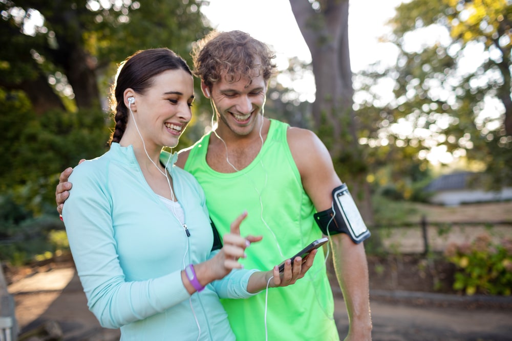 Happy couple checking calories burned on phone during walk