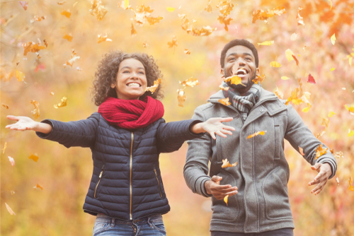 Couple throwing leaves and playing outside