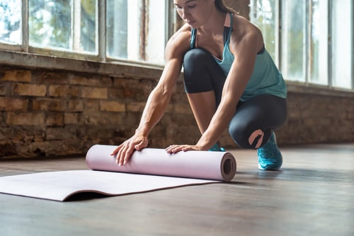 Woman unrolling yoga or pilates mat