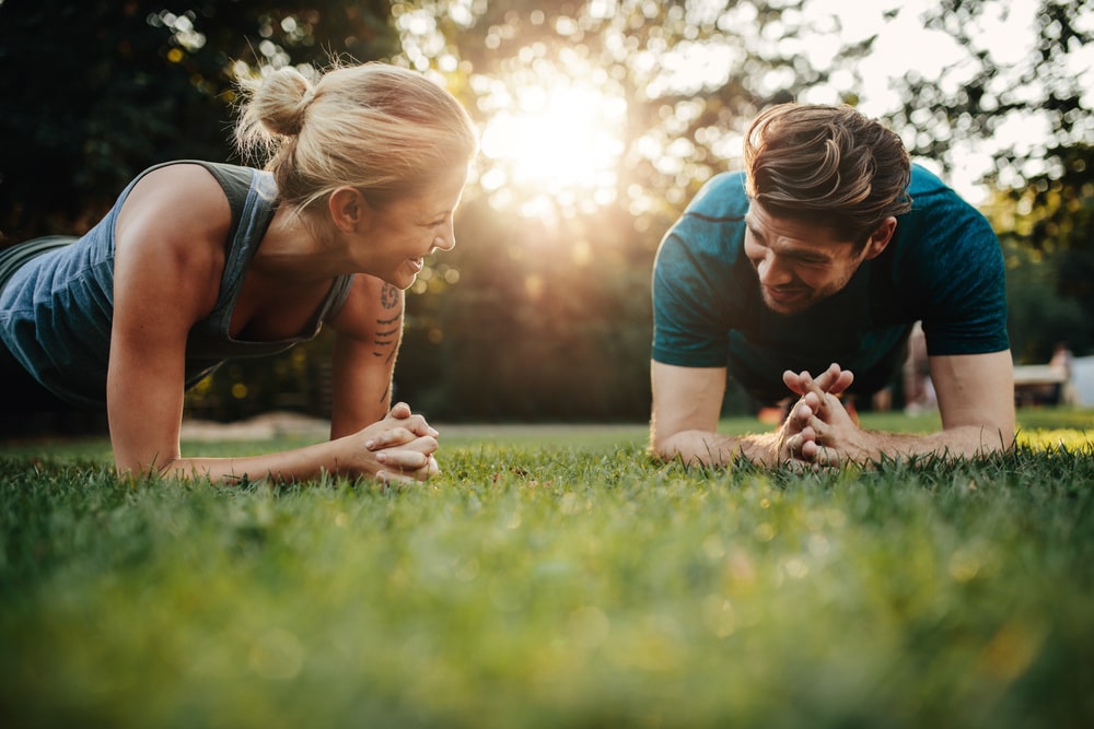 Man and woman doing ab exercises in a park