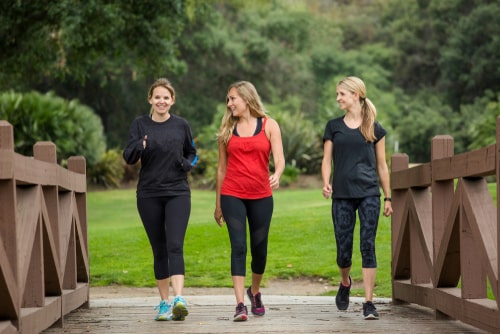 3 women fitness walking across bridge in park
