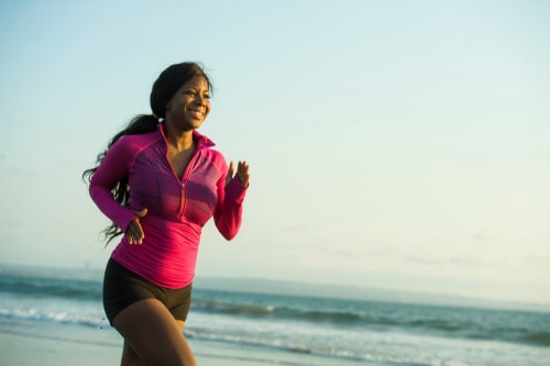 Smiling woman fitness walking by the beach