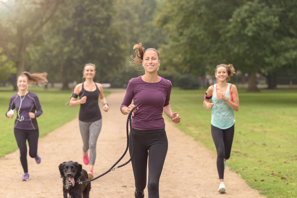 Women jogging in park for fitness with a dog