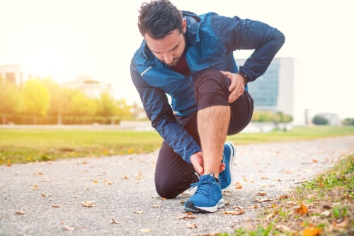 Man checking injured ankle during a park walk