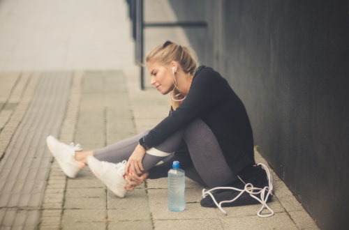 Woman sitting down holding injured ankle