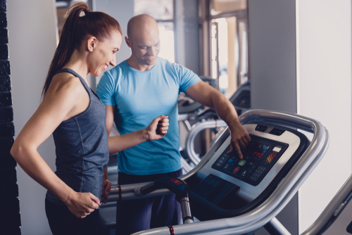 Coach showing woman how to run on treadmill