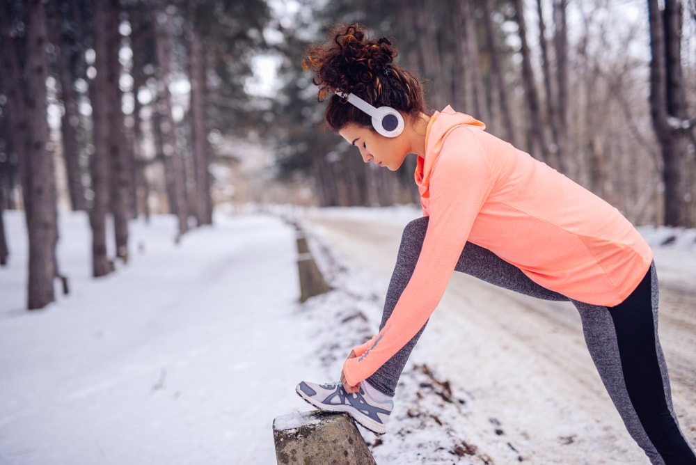 Woman tying her shoes during a snowy walk or jog