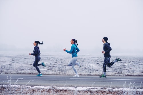 3 people running for fitness on a winter road