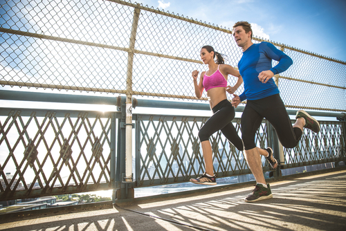 Couple jogging over a bridge in a city