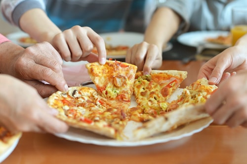 Family sharing pizza - hands reach for slices