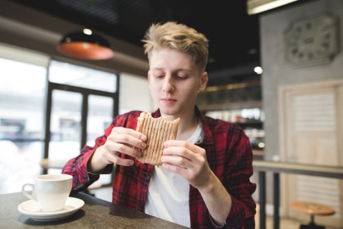 Man drinking coffee and eating sandwich
