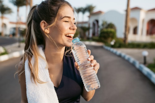 Woman smiling and drinking water during a walk