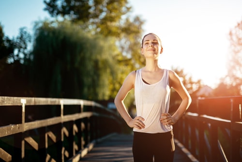 Happy woman standing next to bridge after walking