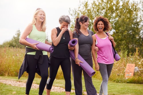 Women walking with yoga mats in the park