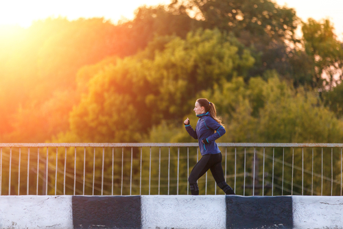 Woman jogging over a bridge in the park