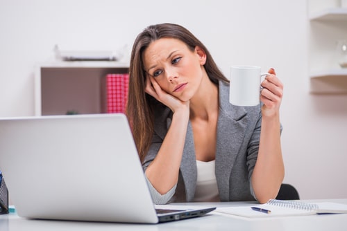 Tired woman drinking coffee in office