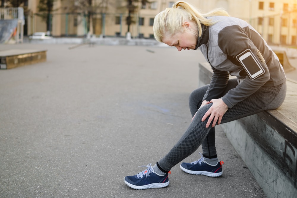 Female fitness walker resting because of knee pain