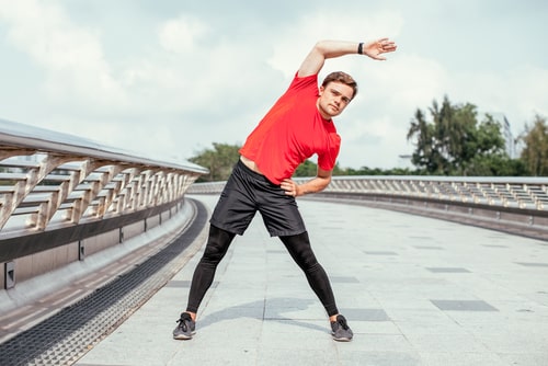 Man doing side stretch during a jog