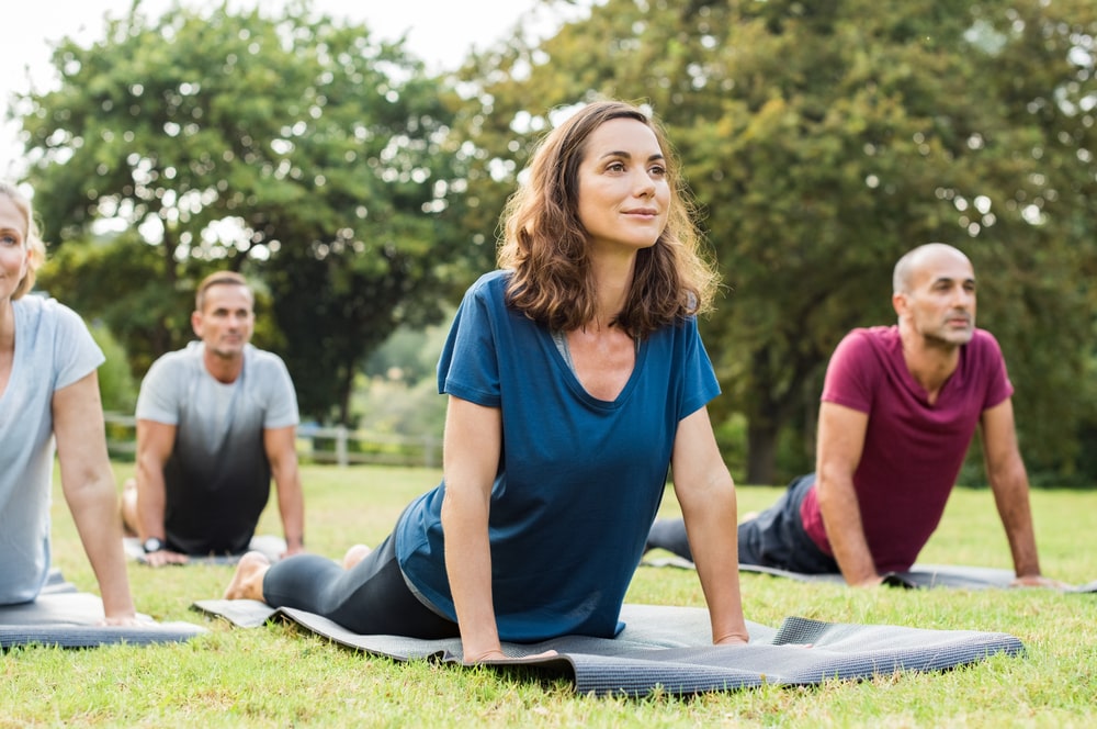 Middle aged adults doing yoga in a park