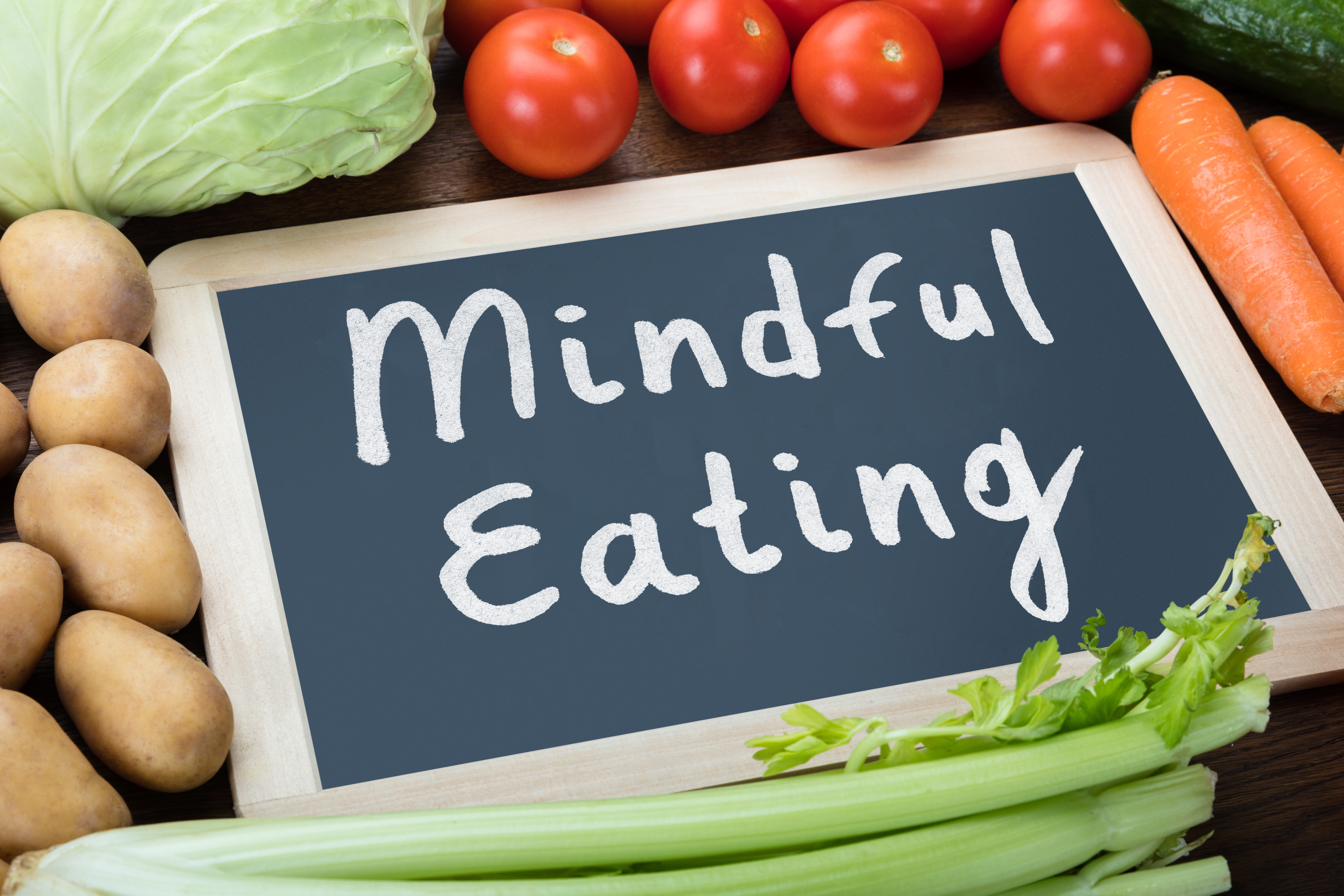 mindful eating text written on chalkboard with vegetables