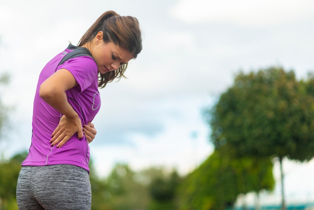 Female walker holding her lower back due to pain