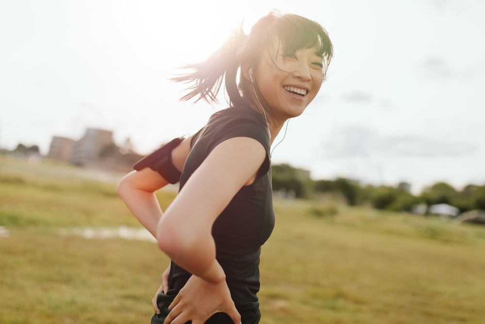 Sporty woman smiling in the sunshine outside
