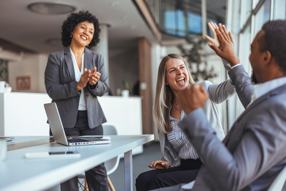 Coworkers celebrating a step challenge milestone with a high five in the office