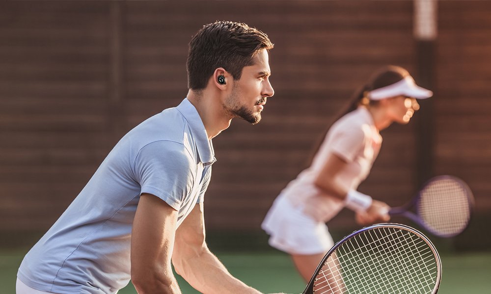 Man playing tennis wearing Tranya earbuds