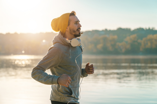 Man fitness walking with headphones near water