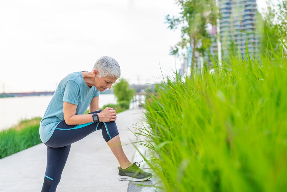 Senior woman holding her knee during a walk