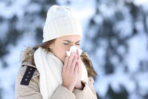 Woman sneezing from a cold in winter