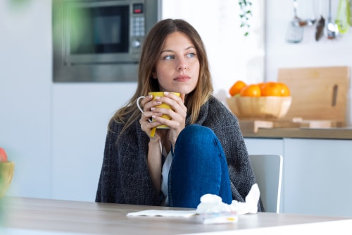 Woman with cold drinking tea at home