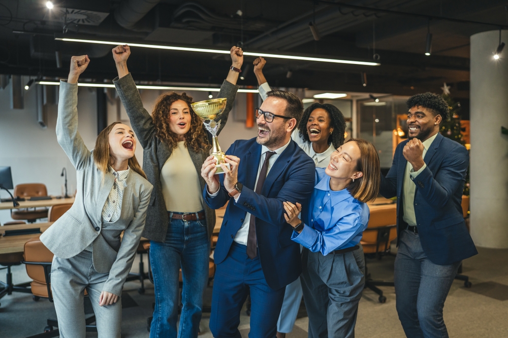 Colleagues high-fiving next to a step challenge prize table with gift cards, a water bottle, and a trophy