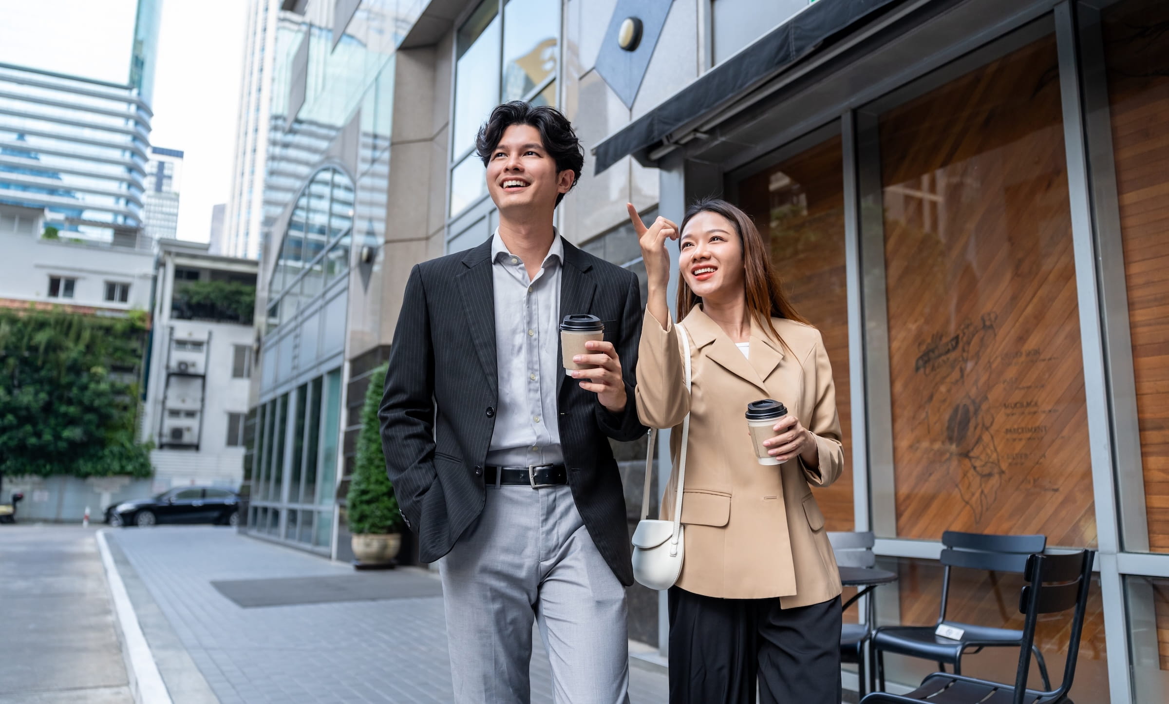 Two coworkers on a workplace step challenge team walking outside with coffee