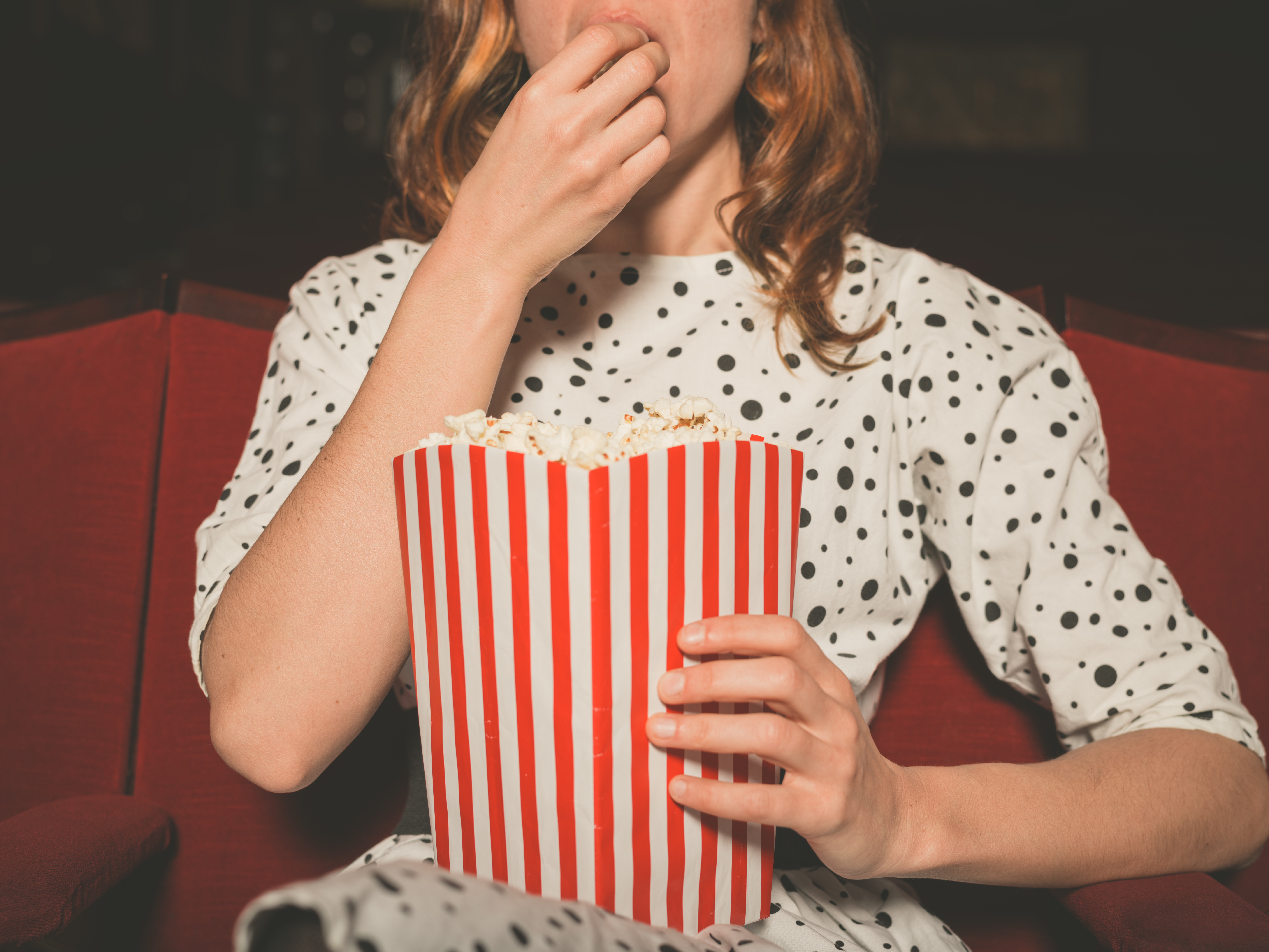 woman eating a large bag of popcorn at the movies