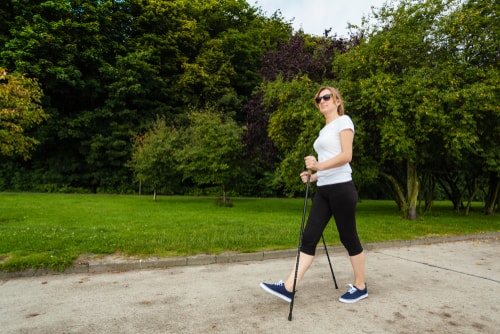 Woman nordic walking in a green park