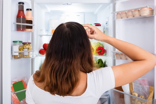 Woman looking at refrigerator deciding what to eat