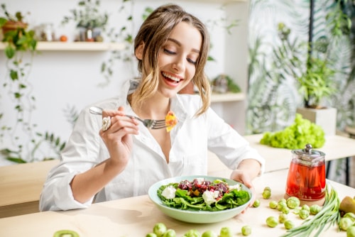 Woman eating salad surrounded by plants