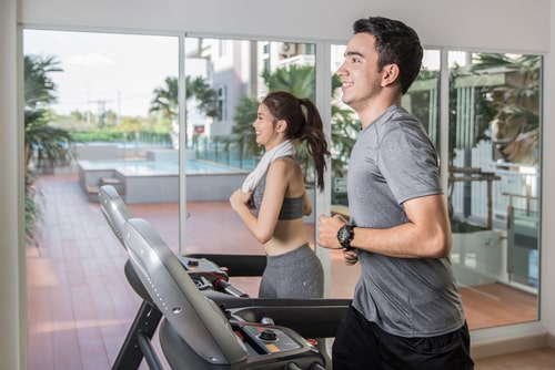 Man and woman running on treadmill at hotel