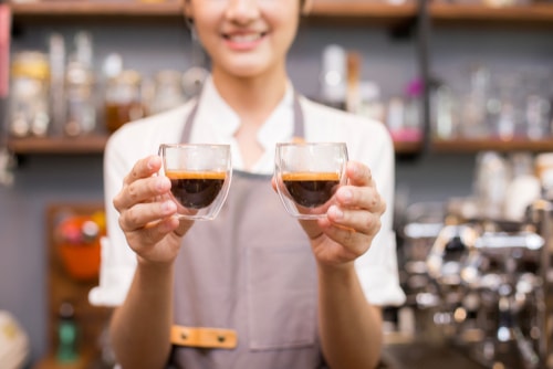 Barista holding shots of espresso