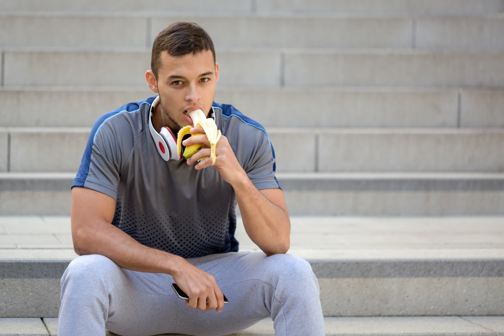 Sporty man eating banana after a walk