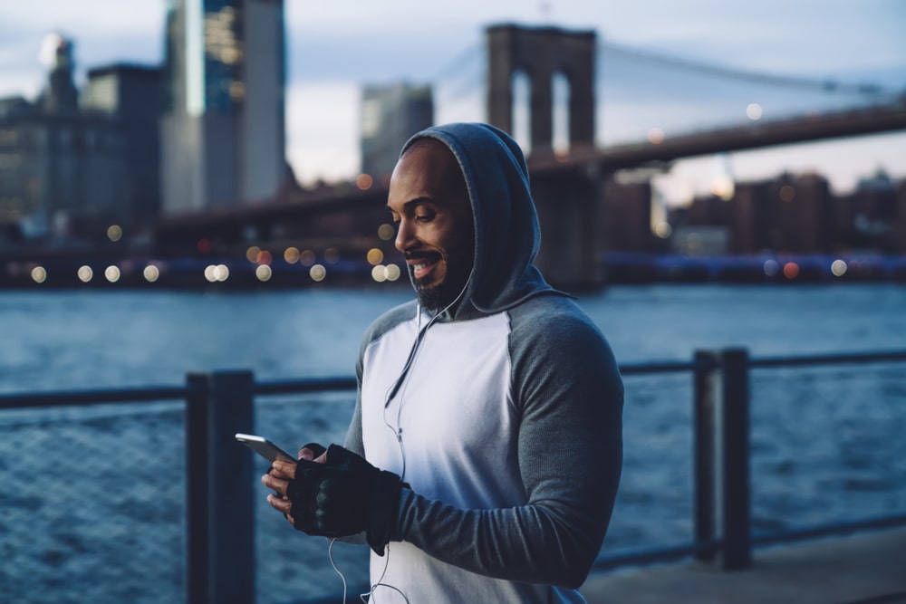Man checking phone on walk with city in background