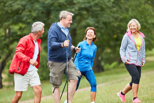 2 senior couples walking with hiking poles in nature