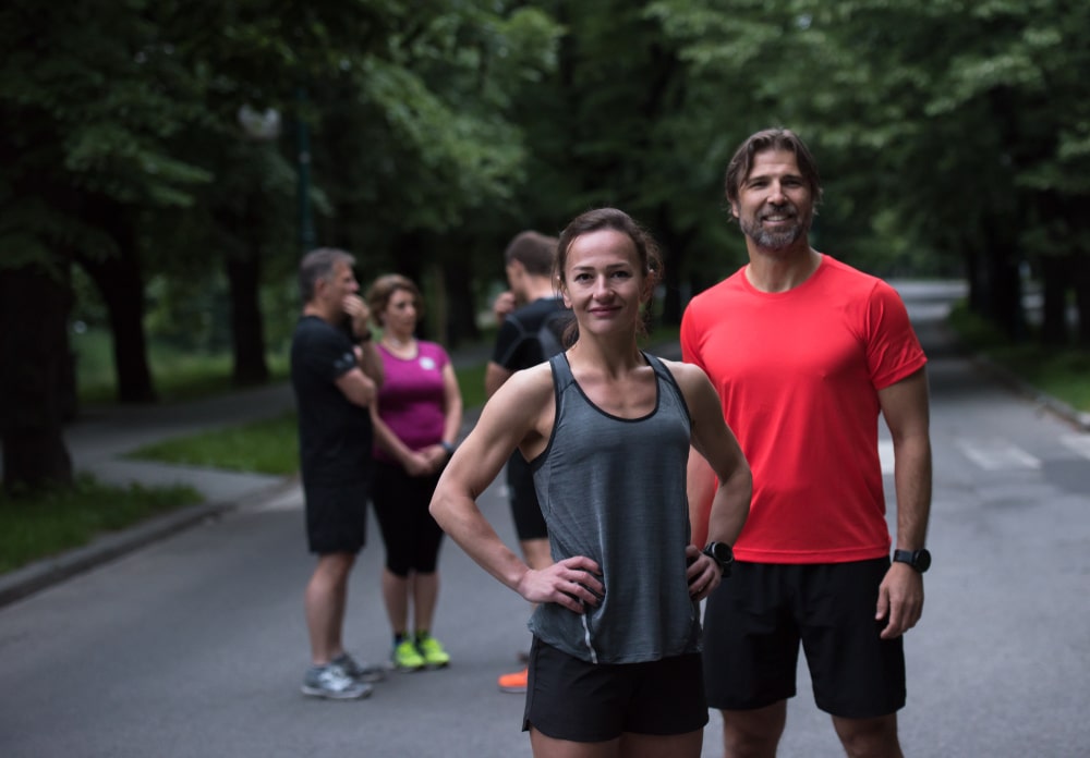 Fit man and woman standing in front of running group
