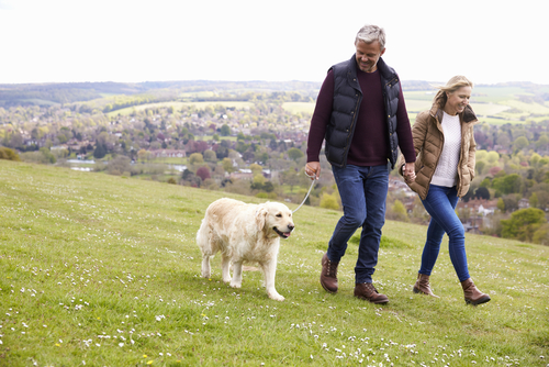 Couple walking dog in hilly terrain