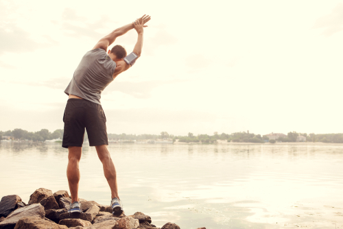 Sporty guy stretching near the water